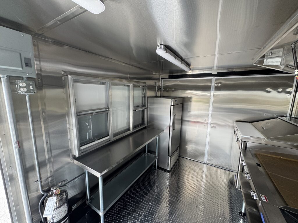 Interior of the Spur Catering food trailer with stainless prep table and reach-in refrigerator
