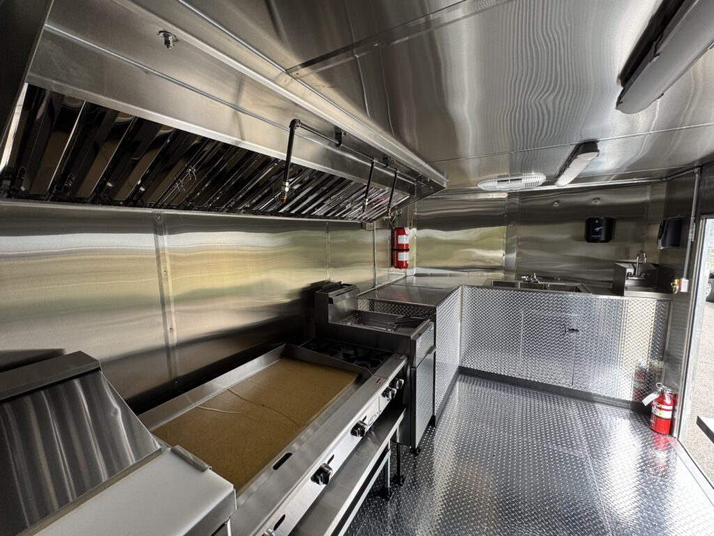 48-inch griddle, 40lb fryer, and range under the exhaust hood in the Spur Catering food trailer
