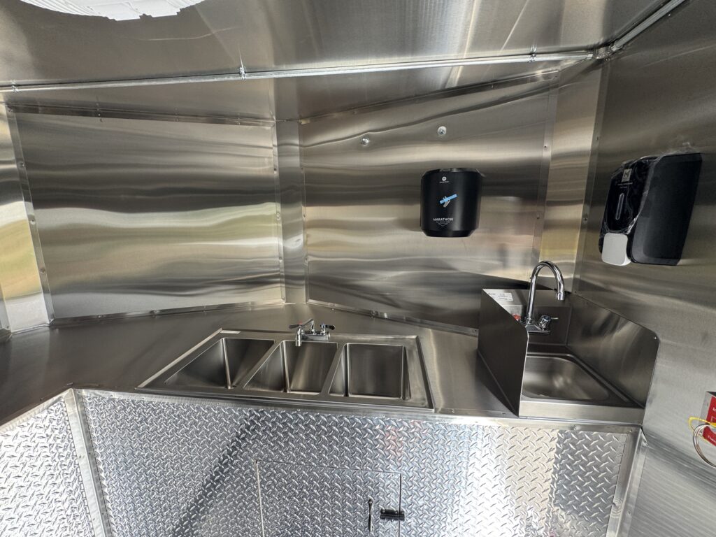Three-compartment sink and separate hand wash sink in the Spur Catering food trailer