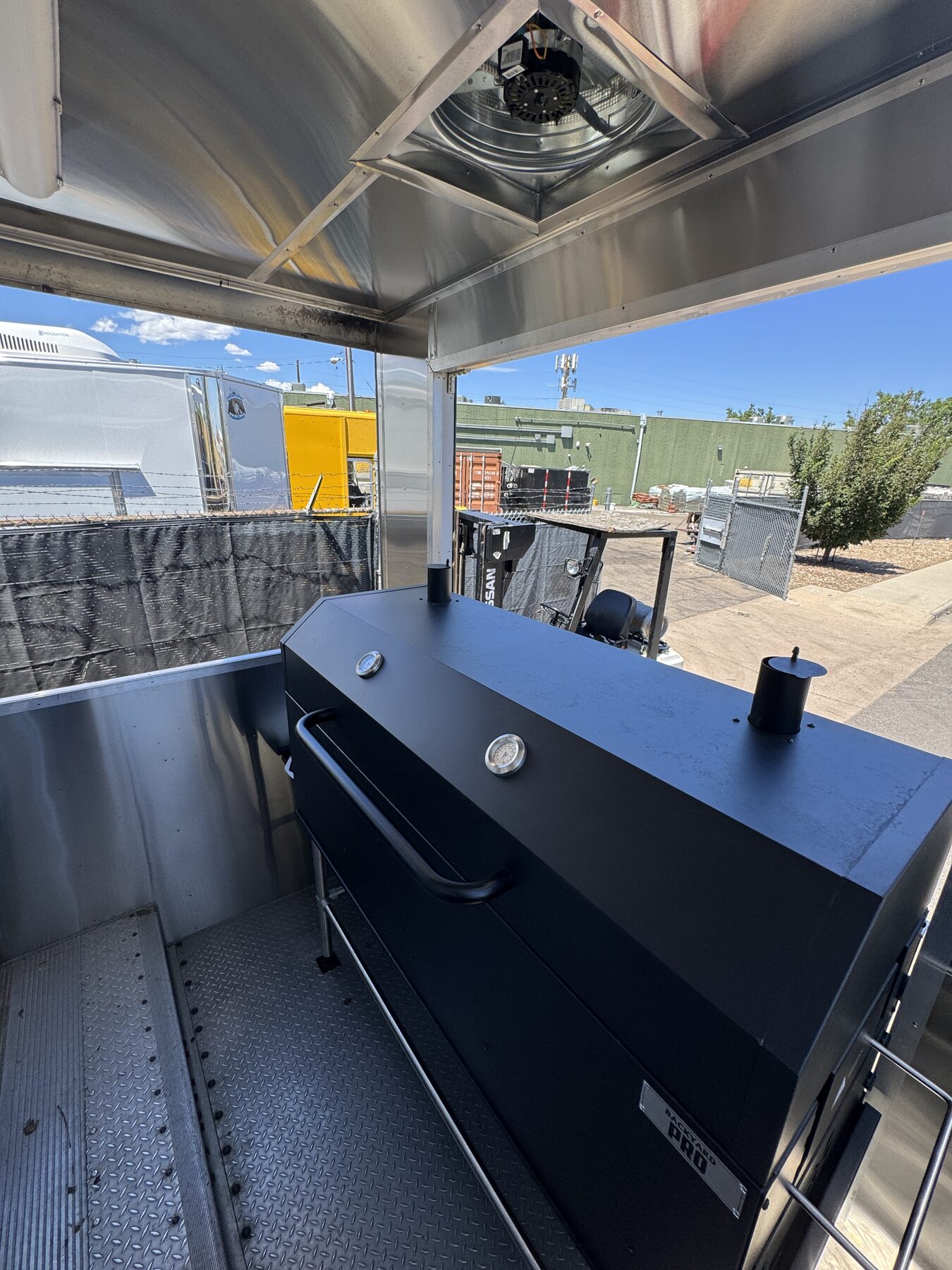 Backyard Pro charcoal smoker mounted on the rear porch of the food truck
