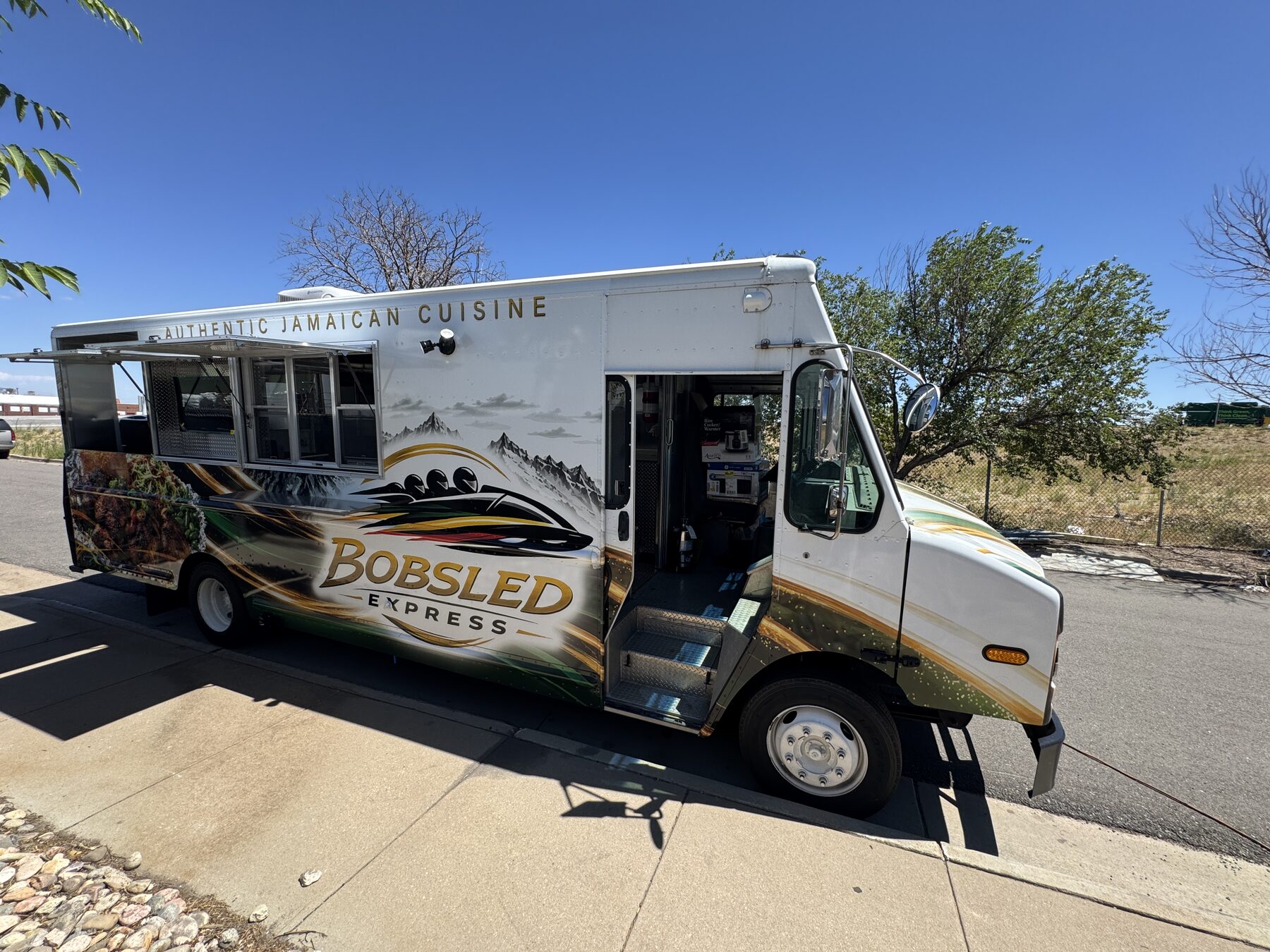 Twenty foot Jamaican food truck built by Mile High Food Trucks, driver side with the entry door open