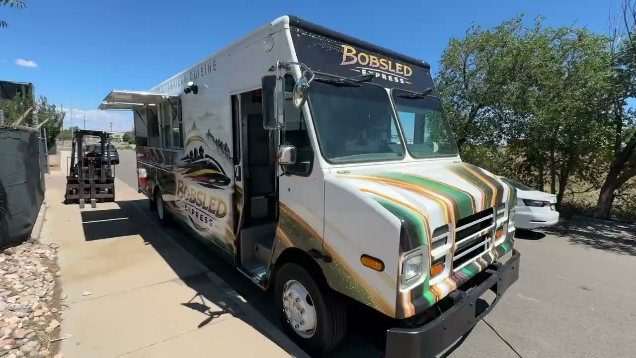 Front three quarter view of the jerk chicken food truck showing the wrap and the underbelly propane tanks