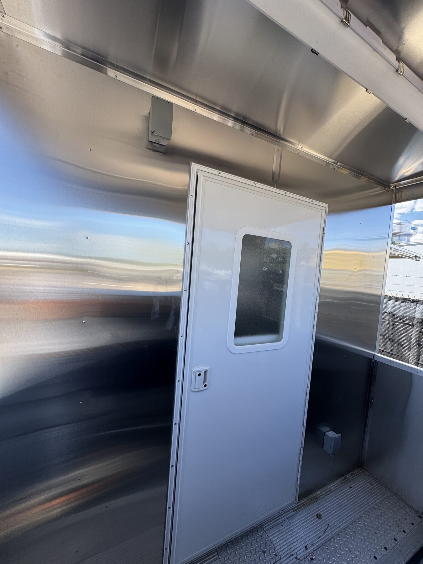 RV door with a window connecting the rear porch to the kitchen of the food truck