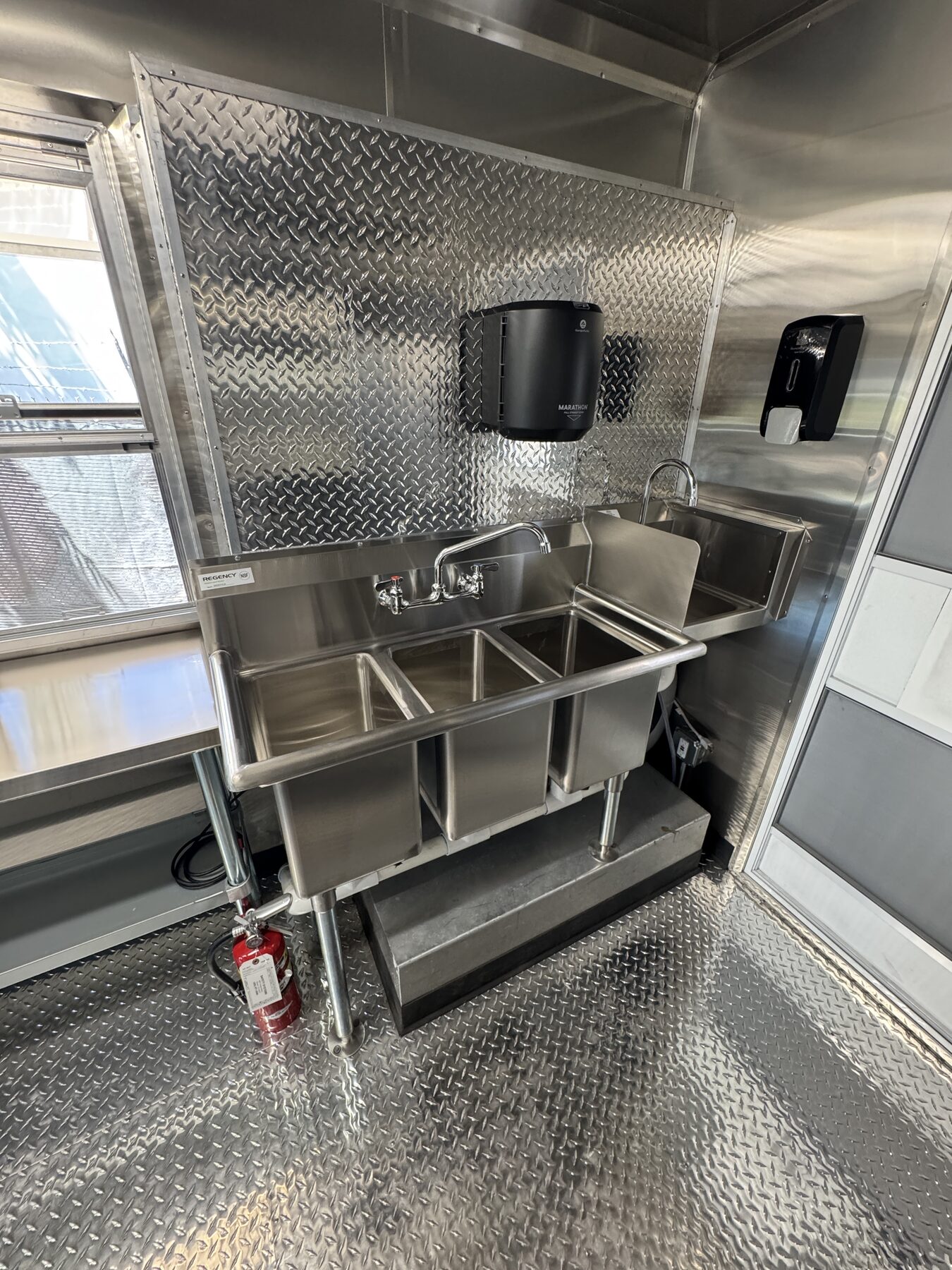 Three compartment sink and hand sink with soap and towel dispensers inside the food truck