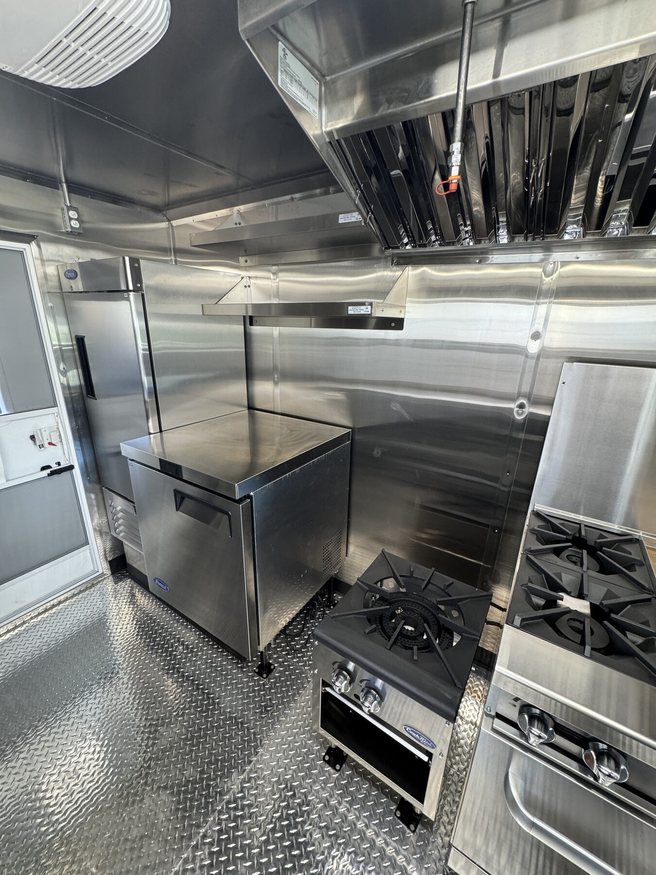 Undercounter freezer, low height reach in refrigerator and single burner stock pot stove along the cook line