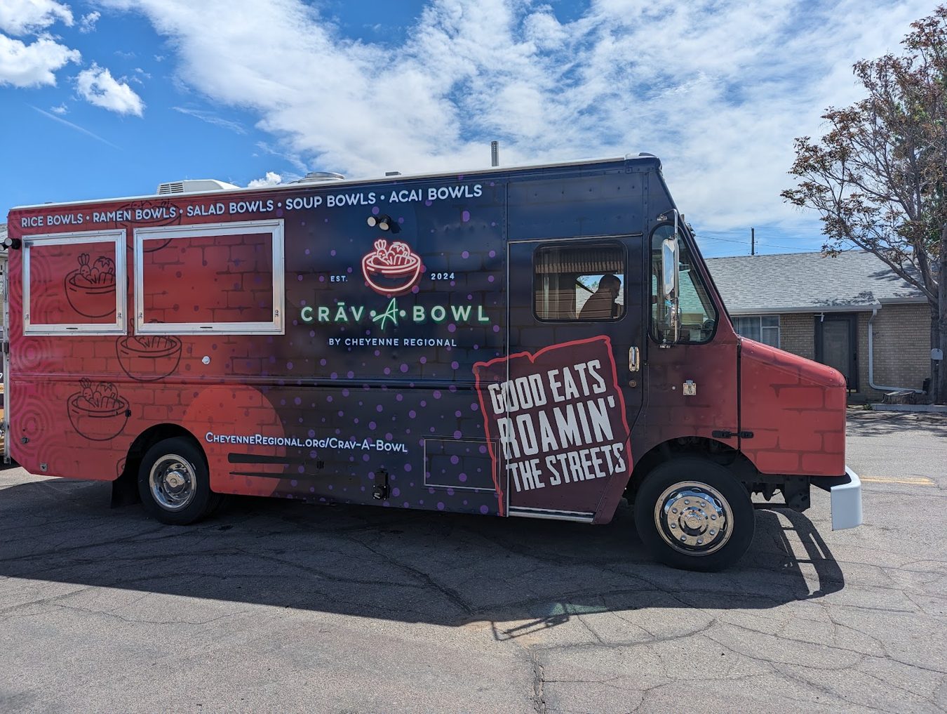 Driver side of the Crav-A-Bowl food truck showing the wrap and the entry door