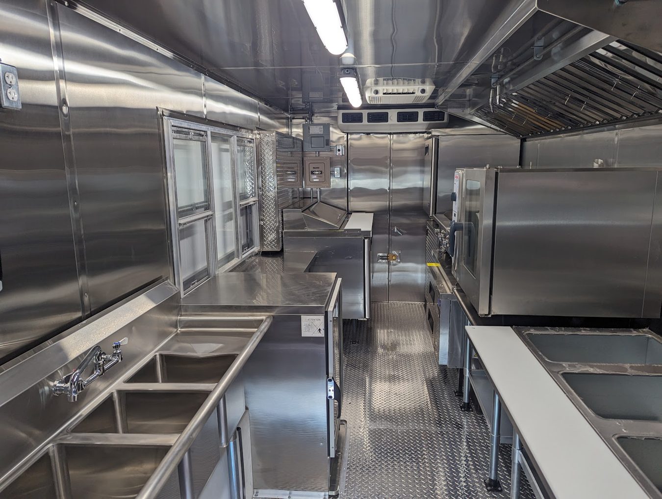 Stainless prep tables and the refrigerated sandwich prep table along the service side of the food truck