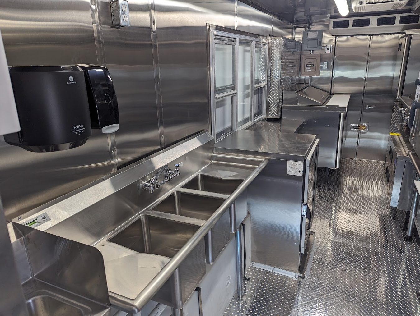 Three compartment sink and hand sink with a towel dispenser inside the stainless steel food truck