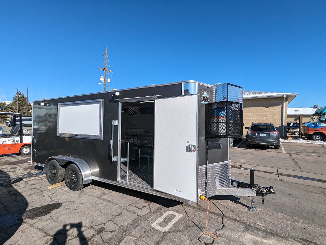 Eighteen foot grey tempura food trailer built by Mile High Food Trucks for Ten Tempura, Lander, Wyoming, curb side with the window and door open